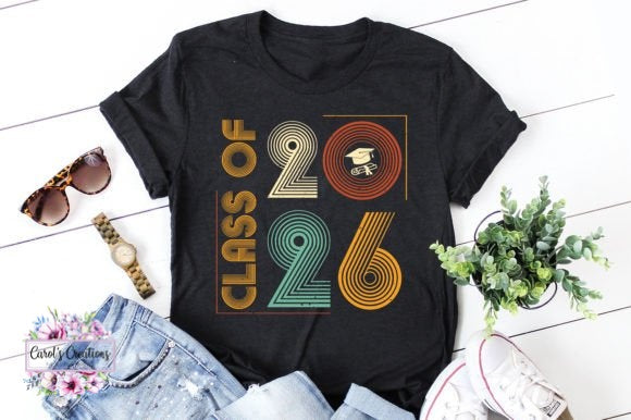 Black t-shirt with 'Class of 2026' design on a white surface with accessories.