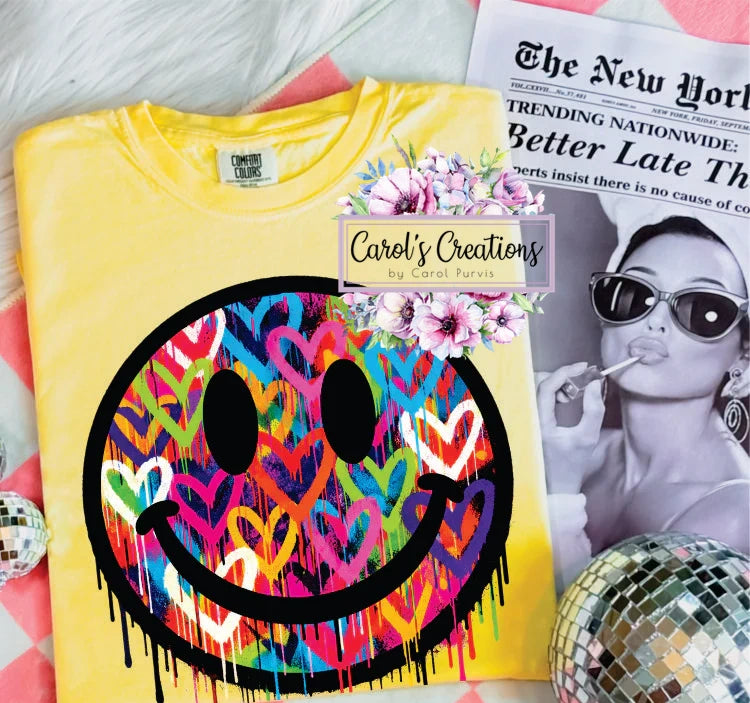 Yellow t-shirt with colorful smiley face design on a surface with a magazine and disco balls.