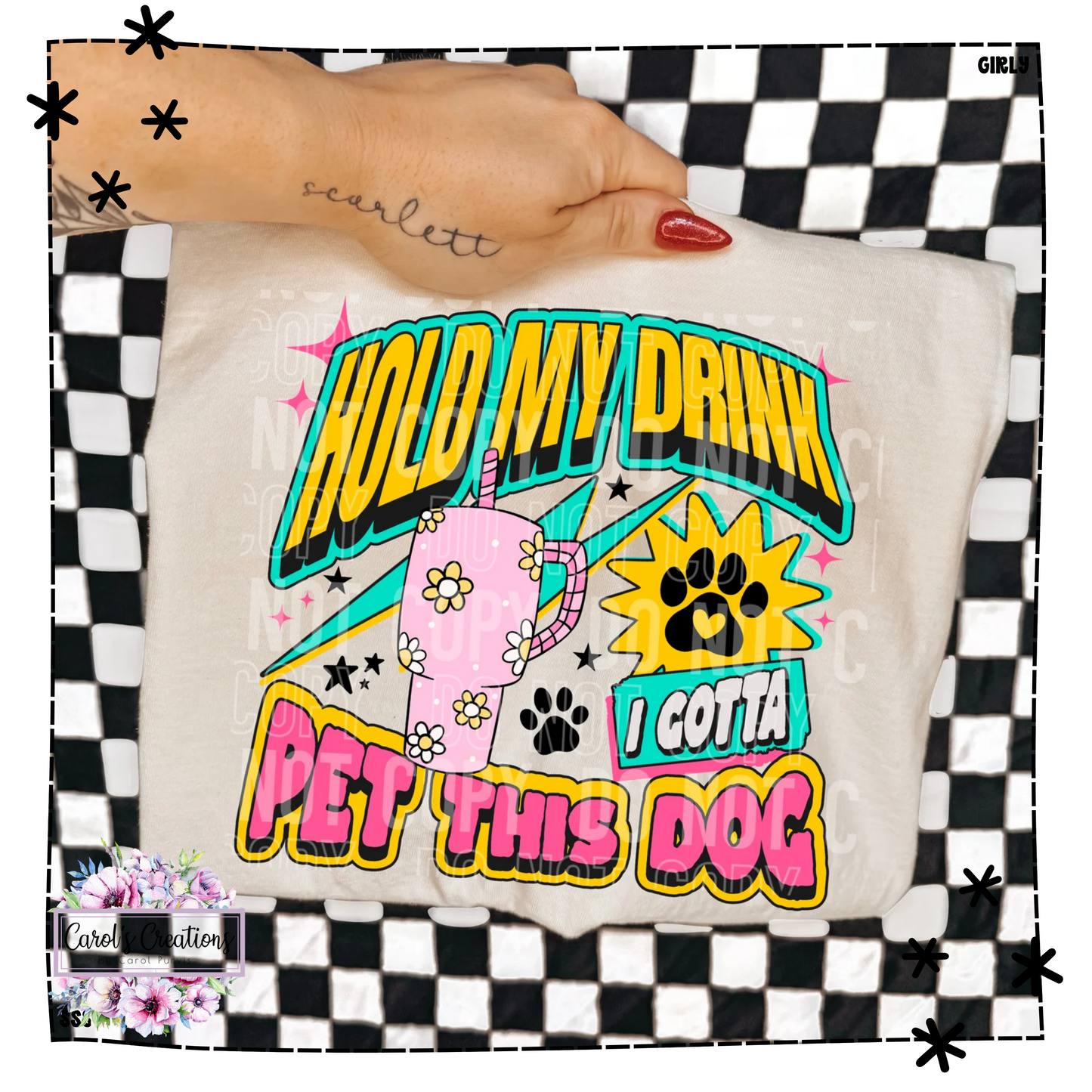 T-shirt with colorful text and graphics held by a hand on a checkered background