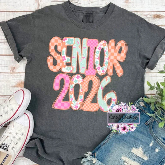 Gray t-shirt with 'Senior 2026' text on a wooden surface with sneakers and jeans.